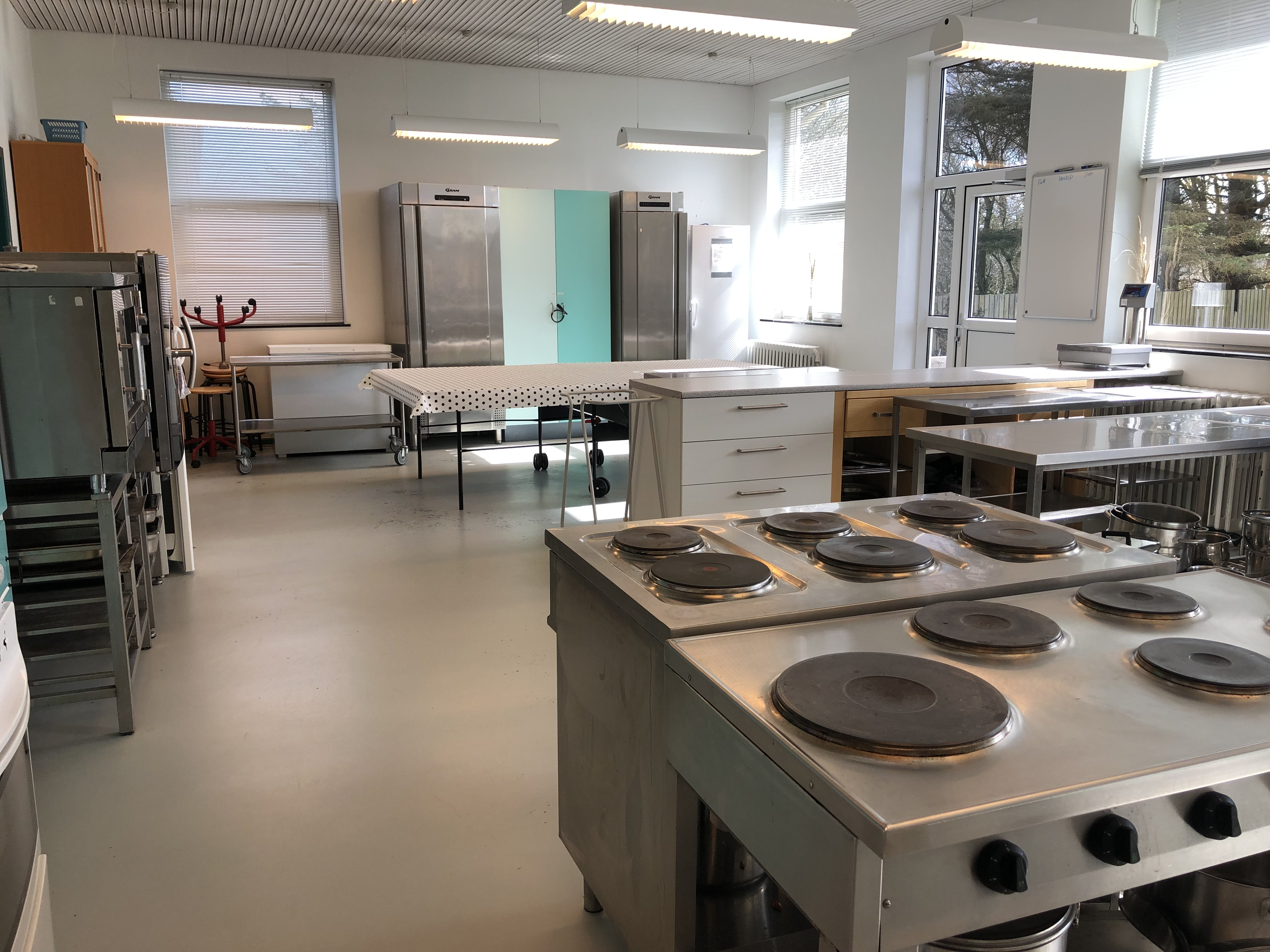<b>Køkken</b><br> Indeholder store ovne, køleskabe, bordplads og service til 80 personer.